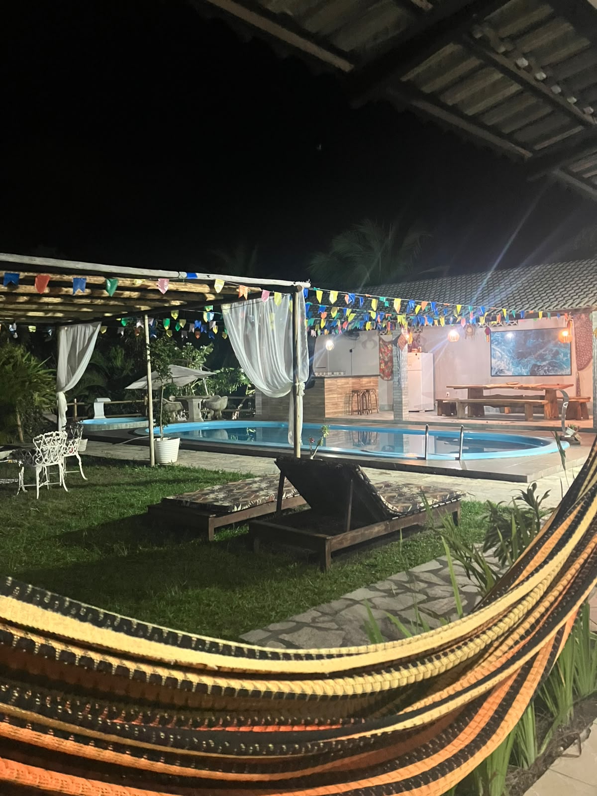 Piscina iluminada e área de descanso à noite